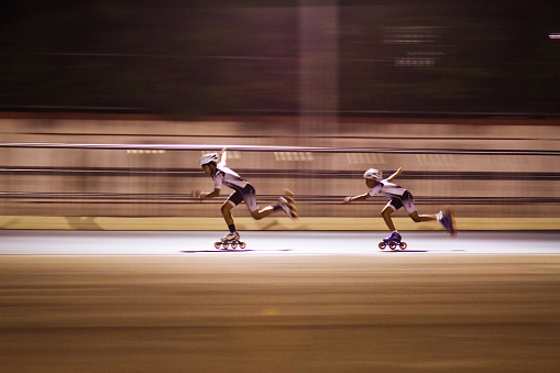 Pune, MH, India - November 12, 2016: Young athletics practicing in the evening in flood lights. Taken this picture in evening at suburban sports fecility near Pune India. Here two young athletics skating fast and hard as well as enjoying it. They are practicing under the floodlights for the upcoming tournament. Tried to capture the speed and motion and the sports persons in their action.