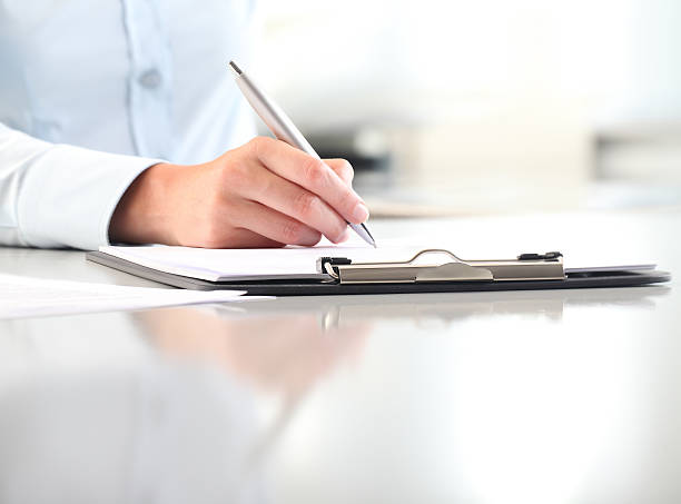 istock woman hands writing on clipboard with a pen 622791702