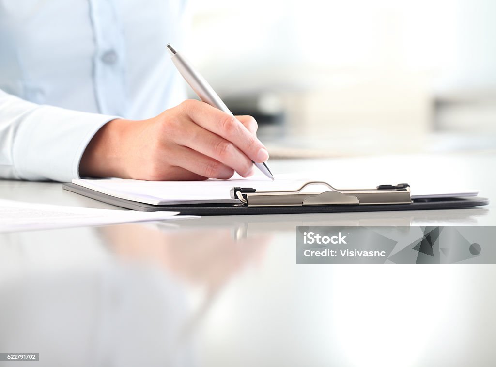woman hands writing on clipboard with a pen woman hands writing on clipboard with a pen, isolated on desk Clipboard Stock Photo