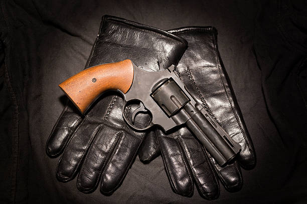 istock Crime concept. Black gun with leather gloves on dark cloth 622793848