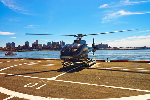 Black Helicopter on helipad in Lower Manhattan New York, USA, on East River. Pier 6. East River and skyscrapers on the background