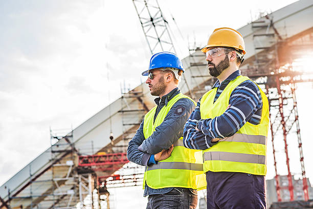 istock Two successful brdge builders near construction platform with arms crossed 622798830