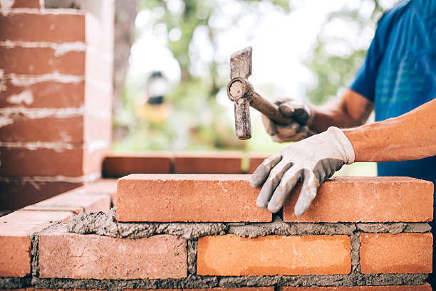 벽돌을 놓기 위해 망치를 사용하여 외부 벽을 쌓는 산업 노동자 - brick cement bricklayer construction 뉴스 사진 이미지