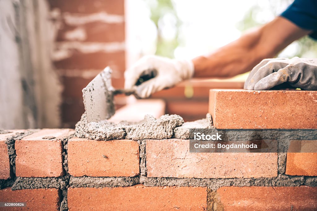 Bricklayer worker installing brick masonry on exterior wall Bricklayer worker installing brick masonry on exterior wall with trowel putty knife Masonry Stock Photo