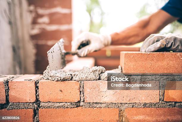 Bricklayer Worker Installing Brick Masonry On Exterior Wall Stock Photo - Download Image Now