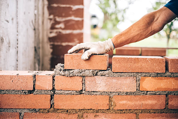 albañil industrial colocando ladrillos sobre cemento mientras construye paredes - construction material material brick building activity fotografías e imágenes de stock