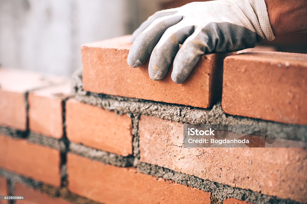 Close up of industrial bricklayer installing bricks on construction site Construction Industry Stock Photo