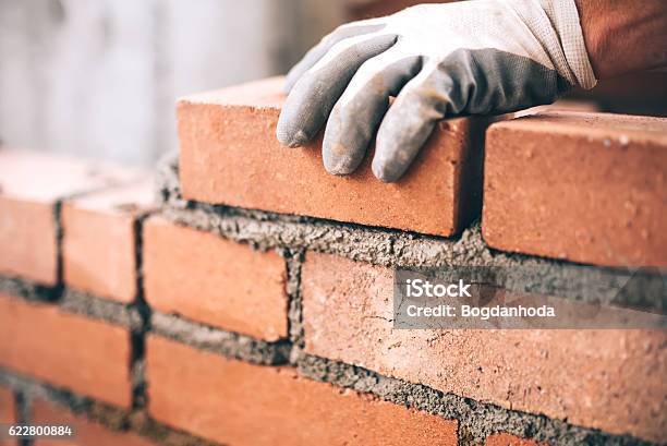 Close Up Of Industrial Bricklayer Installing Bricks On Construction Site Stock Photo - Download Image Now