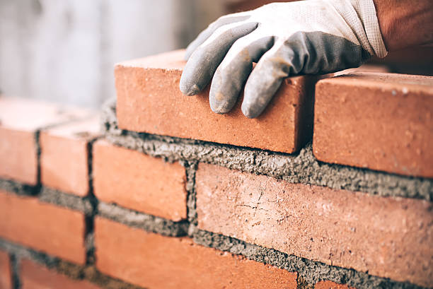 close up of industrial bricklayer installing bricks on construction site - manual worker fotos imagens e fotografias de stock