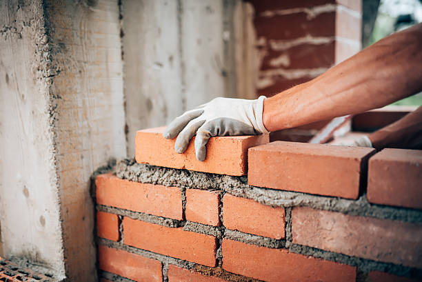 Construction worker laying bricks on exterior walls stock photo