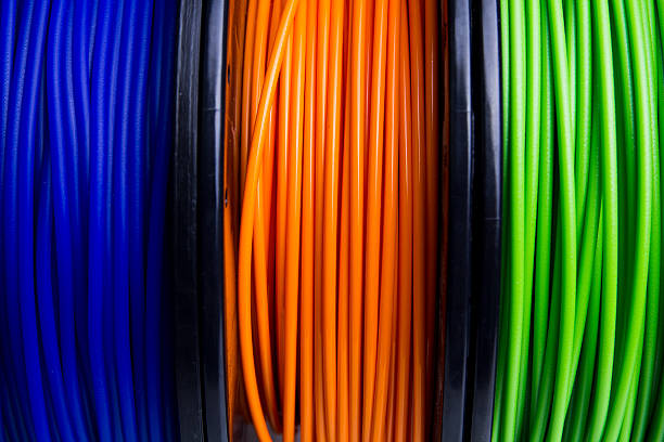 Close-up of multiple colored 3D printer filament spools Close-up of blue, orange and green 3D printer filament spools 3d printing filament photos stock pictures, royalty-free photos & images