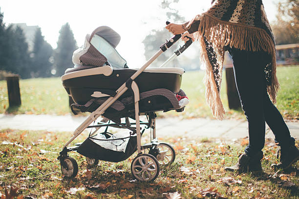 junge mutter mit einem baby-kinderwagen - sportkinderwagen stock-fotos und bilder