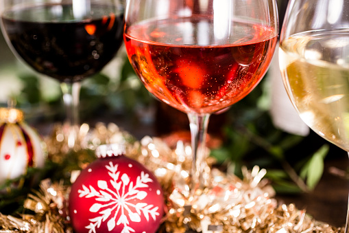 Wine tasting event at Christmas party. Red, rose, and white wine selections on dining table with holiday decorations during party or wine tasting event.  Wine bottles in background.   No people.