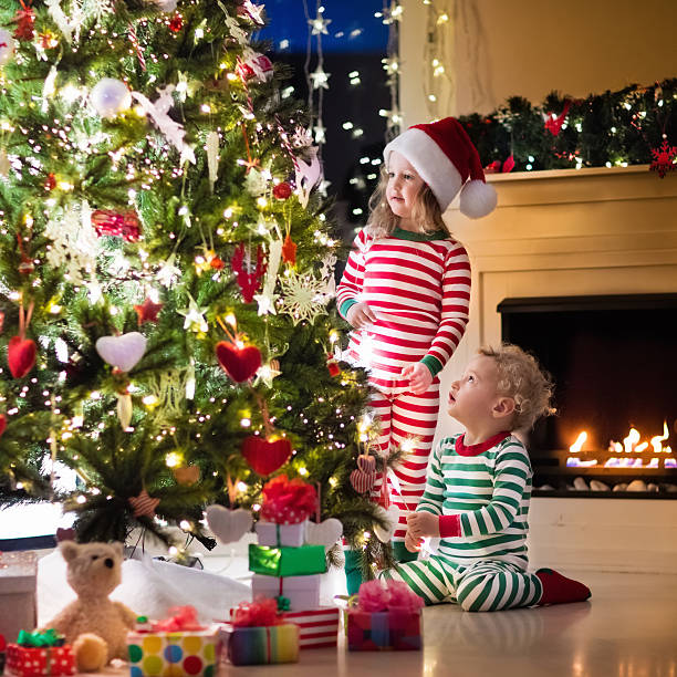 istock Kids in red and green striped pajamas under Christmas tree 622810054