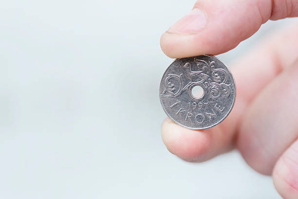 istock Norwegian krone with hole in it held by fingers 622891926