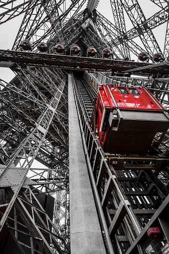 Photography of a red elevator located in the famous metal structure of the Eiffel Tower. This elevator goes up and down to the service and maintenance staff of the tower. It can not be used by tourists who visit daily the iron monument built in the wonderful city of light, Paris.