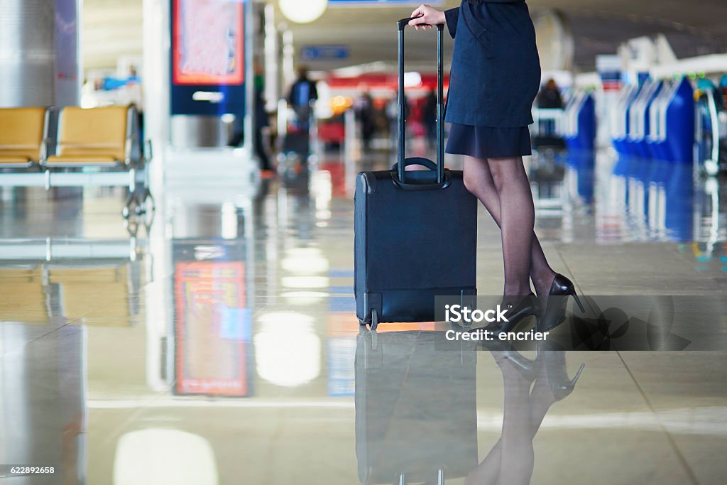 Young female traveler in international airport Beautiful female passenger or flight attendant in international airport with hand luggage Air Stewardess Stock Photo
