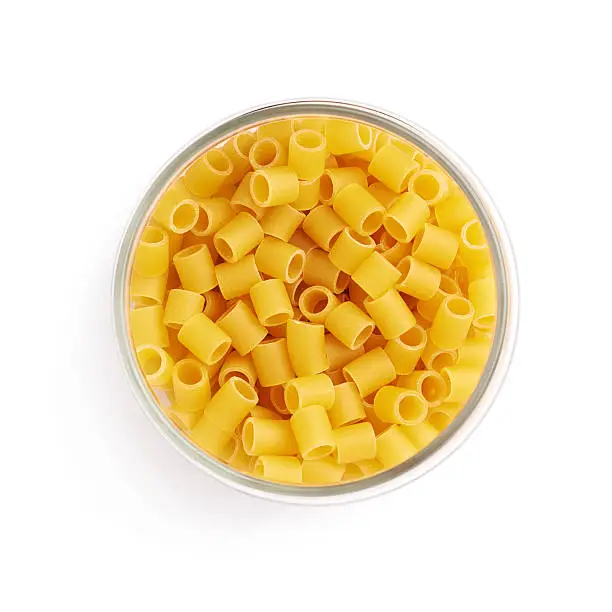 Glass jar filled with dry ditalini yellow pasta over isolated white background
