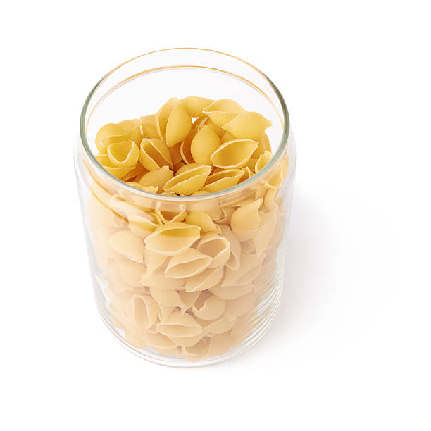 istock Glass jar filled with dry conchiglie pasta over isolated white 622897582