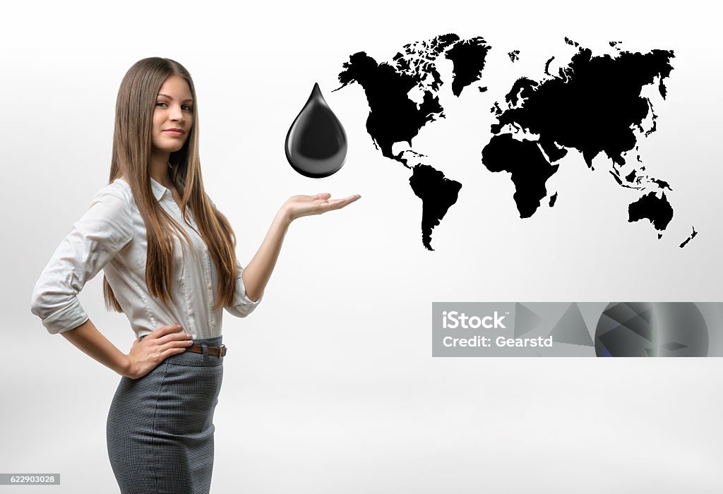 Beautiful businesswoman standing with big oil drop above her open A beautiful businesswoman standing with a big oil drop above her open palm on the white background with the black outlines of the continents. Oil and petroleum products. The most valuable commodities of our lifetime. Black gold. Resource extraction. Adult Stock Photo