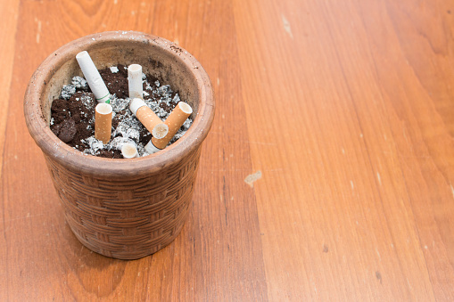 cigarette in ashtray on wooden background with copy space