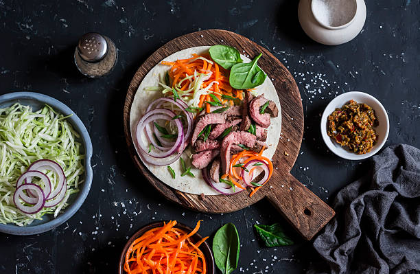 Steak tortilla with pickled carrots and cabbage Steak tortilla with pickled carrots and cabbage on a wooden cutting board on dark background, top view steak salad stock pictures, royalty-free photos & images