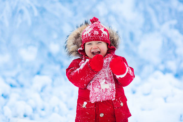 istock Laughing baby playing with snow in winter park 622906650