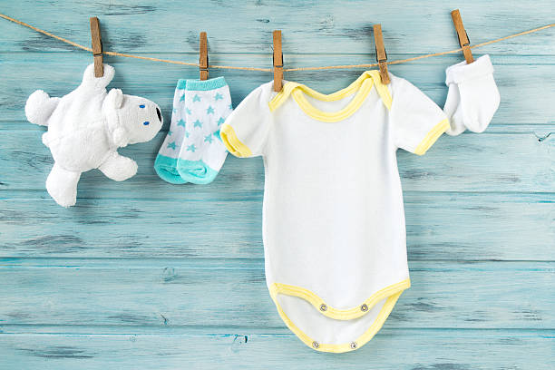 baby-kleidung, body, socken, weißes bärenspielzeug auf einer wäscheleine - babybekleidung stock-fotos und bilder