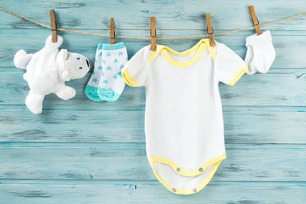 Photo of Baby clothes, onesie, socks, white bear toy on a clothesline