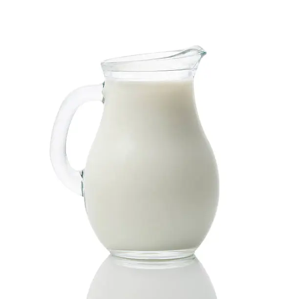 Glass jug full of fresh milk isolated on white background