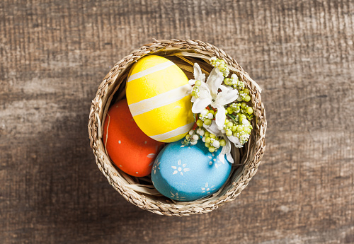 Painted colorful easter eggs of red, yellow and blue colors in a nest on grunge wooden background