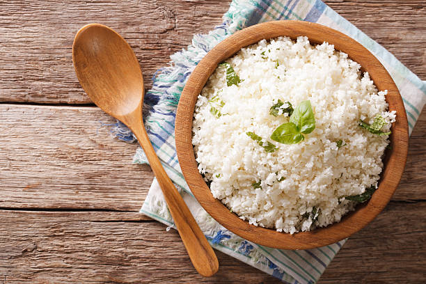 Cauliflower rice with basil in bowl close-up. Horizontal top view