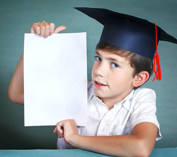 istock boy in graduation cap whith white paper sheet 622919776