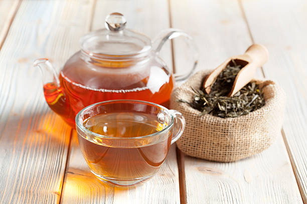 Cup of tea, teapot and tea leaves on wooden table stock photo