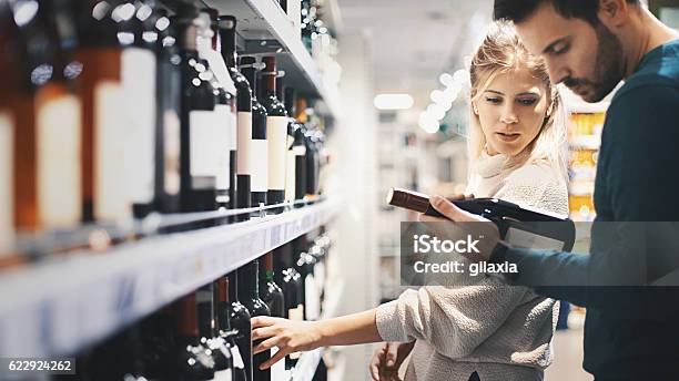 Couple Buying Some Wine At A Supermarket Stock Photo - Download Image Now - Wine, Shopping, Retail
