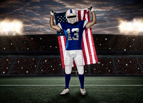 Football Player with a blue uniform and a american flag, on a stadium.