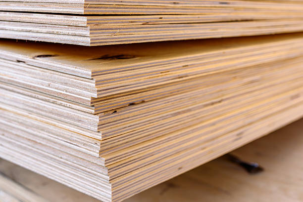 Plywood Sheets of stacked plywood in lumberyard. Shallow focus and blurred background. Copy space. Plywood stock pictures, royalty-free photos & images