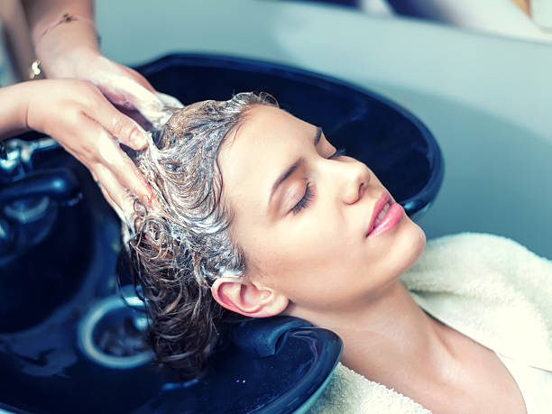 Washing Hair in Hair Salon Young woman washing hair in salon washing hair stock pictures, royalty-free photos & images