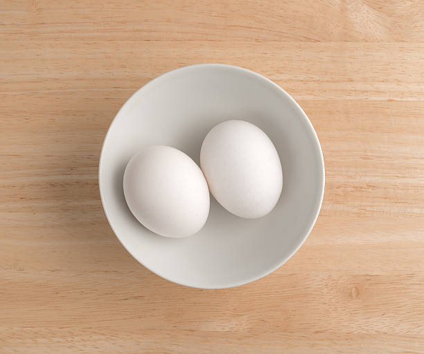 나무 테이블 꼭대기에 그릇에 두 개의 계란. - two eggs 뉴스 사진 이미지