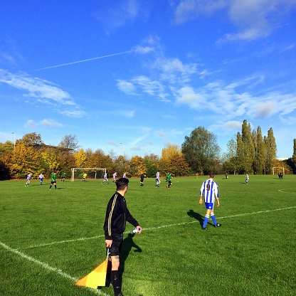 Bracknell,England - November 13, 2016: An official linesman with his flag keeps his eye on a game of amateur football being played on a sunny Autumn day in Bracknell, England