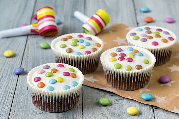 istock Chocolate cupcakes glazed with smarties, wooden background 622959096