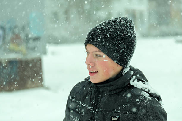 Mid age boy wearing winter hat looking surprised under nsow