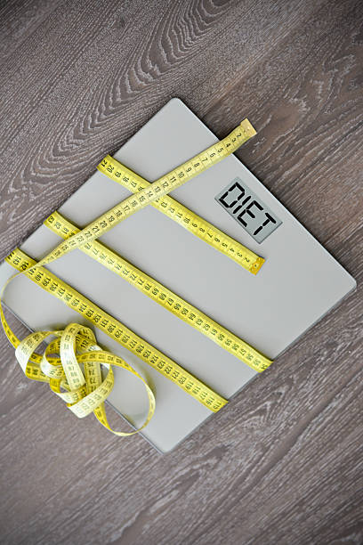 istock Measuring tape and weight scale spelling “diet” on display 622963742
