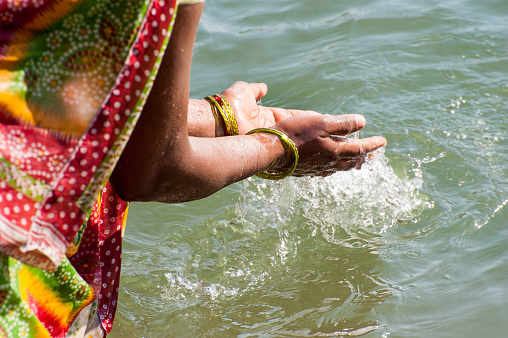 Prayer, hands pouring sacred water to Mandakini river during the daily worship, Chitrakoot, India