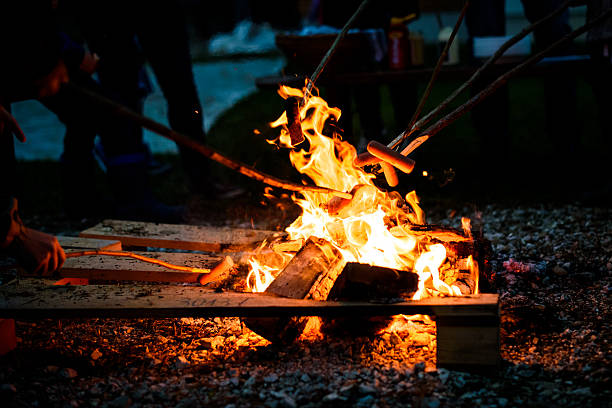 Making and cooking Hot dog sausages over open camp fire.