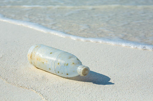 A drinking water bottle fell off a boat into the sea, and later washed ashore an island. This man-made waste takes decades to decompose. It can be properly handled, such as recycling.