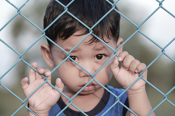 istock The boy standing of  pulling a metal fence . 622969118