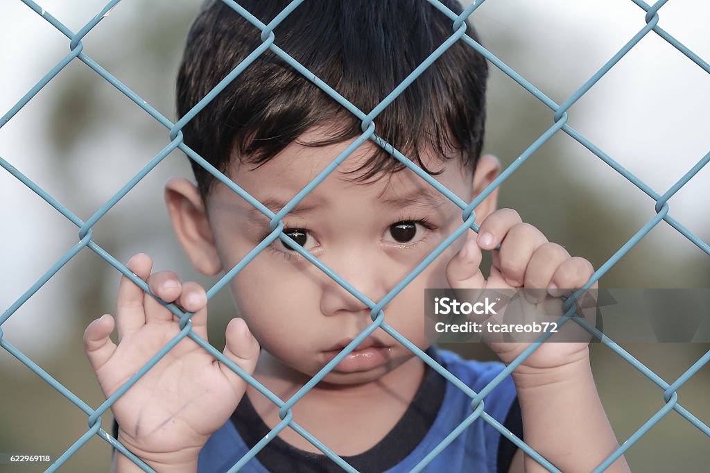 The boy standing of  pulling a metal fence . Child Stock Photo