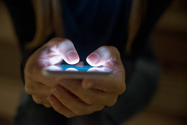 mujer que usa su teléfono móvil afuera por la noche - mensaje de texto fotos fotografías e imágenes de stock