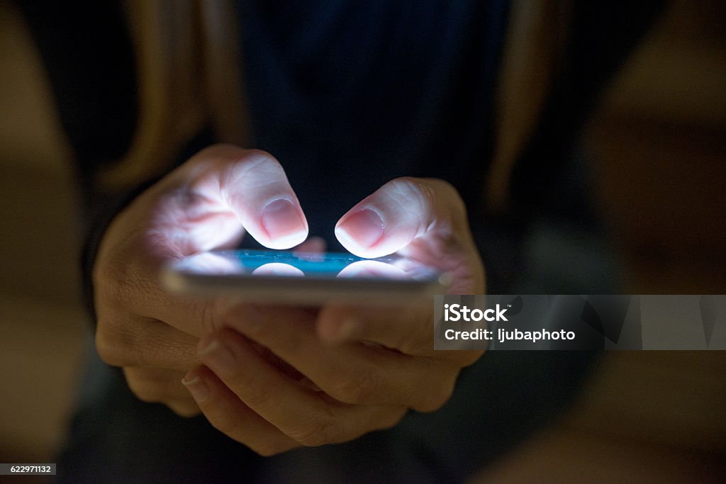Female using her mobile phone outside at night Telephone Stock Photo